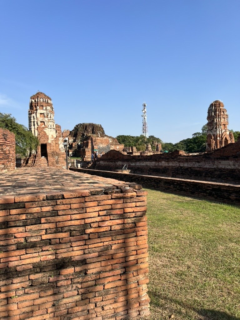 アユタヤの寺院遺跡。青空の下に赤レンガの仏塔と遺構が広がる