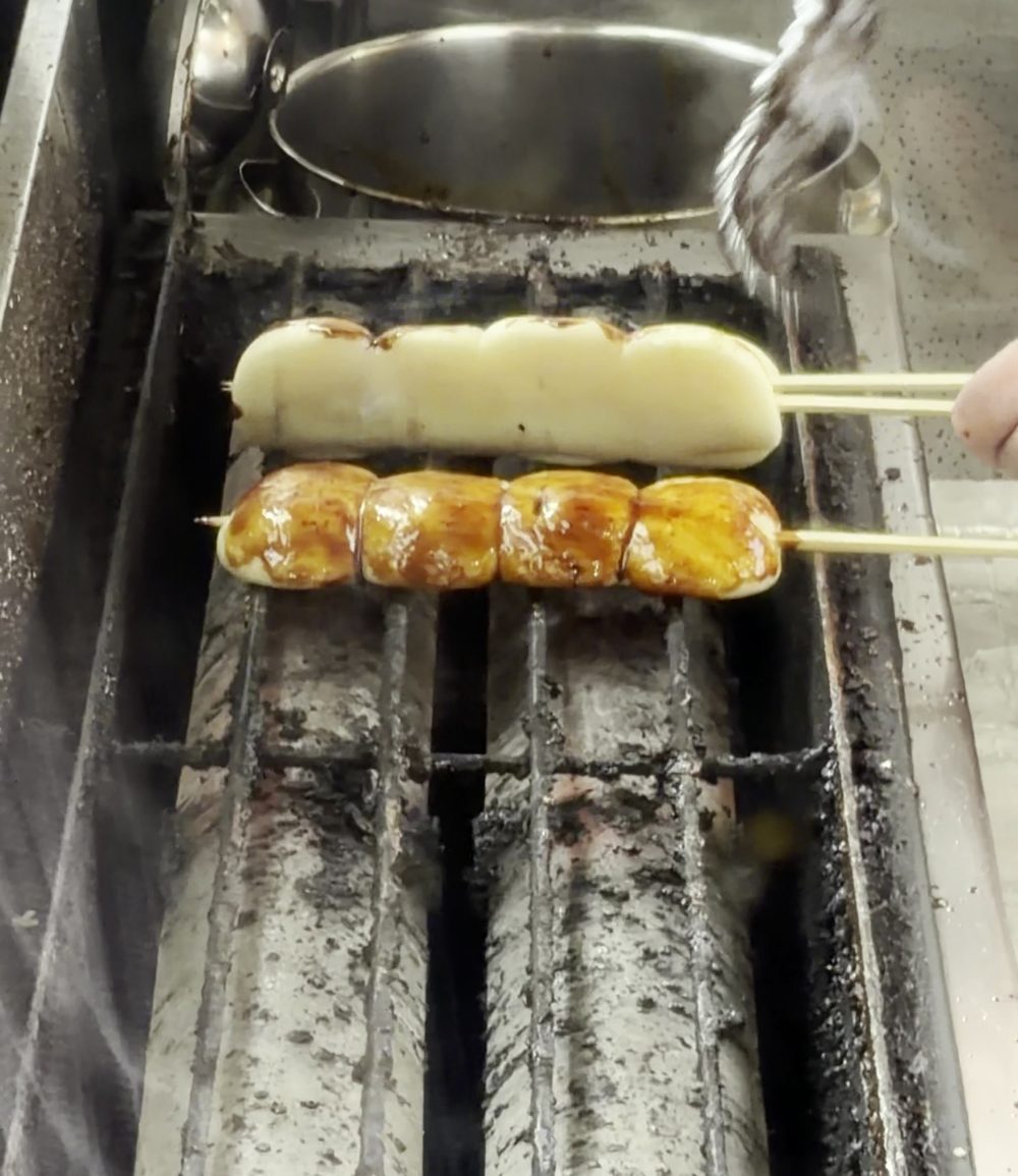 田舎やの焼きまんじゅう。串に刺したまんじゅうに甘辛いタレを塗って焼いている